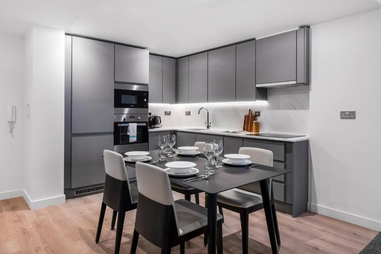 Citysuites 2 Aparthotel Manchester Zewnętrze zdjęcie The photo shows a modern kitchen and dining area. The kitchen features sleek, gray cabinetry and a countertop that complements the overall aesthetic. There are built-in appliances, including an oven and refrigerator, arranged neatly. Next to the kitc
