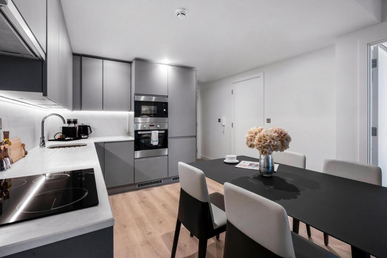 Citysuites 2 Aparthotel Manchester Zewnętrze zdjęcie The photo shows a modern kitchen and dining area. The kitchen features sleek gray cabinets, a countertop with an embedded cooktop, and built-in appliances, including an oven and microwave. There’s a small coffee maker on the counter. Adjacent to the 