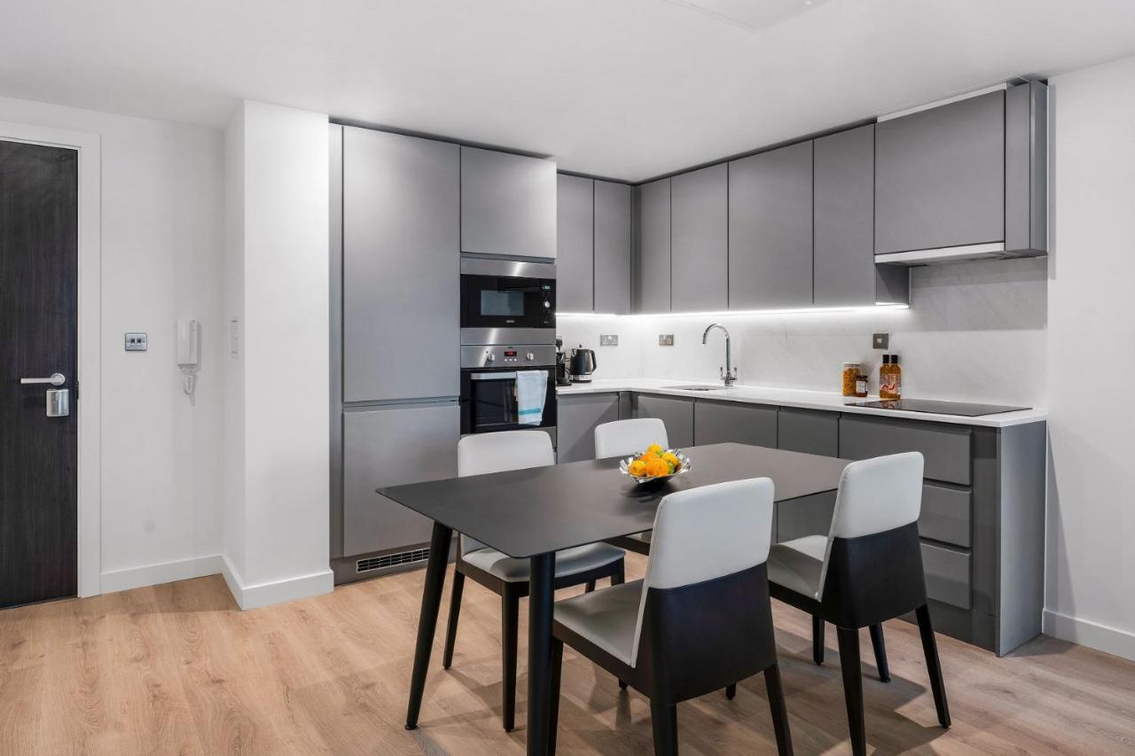 Citysuites 2 Aparthotel Manchester Zewnętrze zdjęcie The photo shows a modern kitchen with a sleek and minimalist design. The cabinetry features a gray finish, and there are built-in appliances, including an oven and possibly a microwave. The countertop is light-colored, providing contrast to the darke