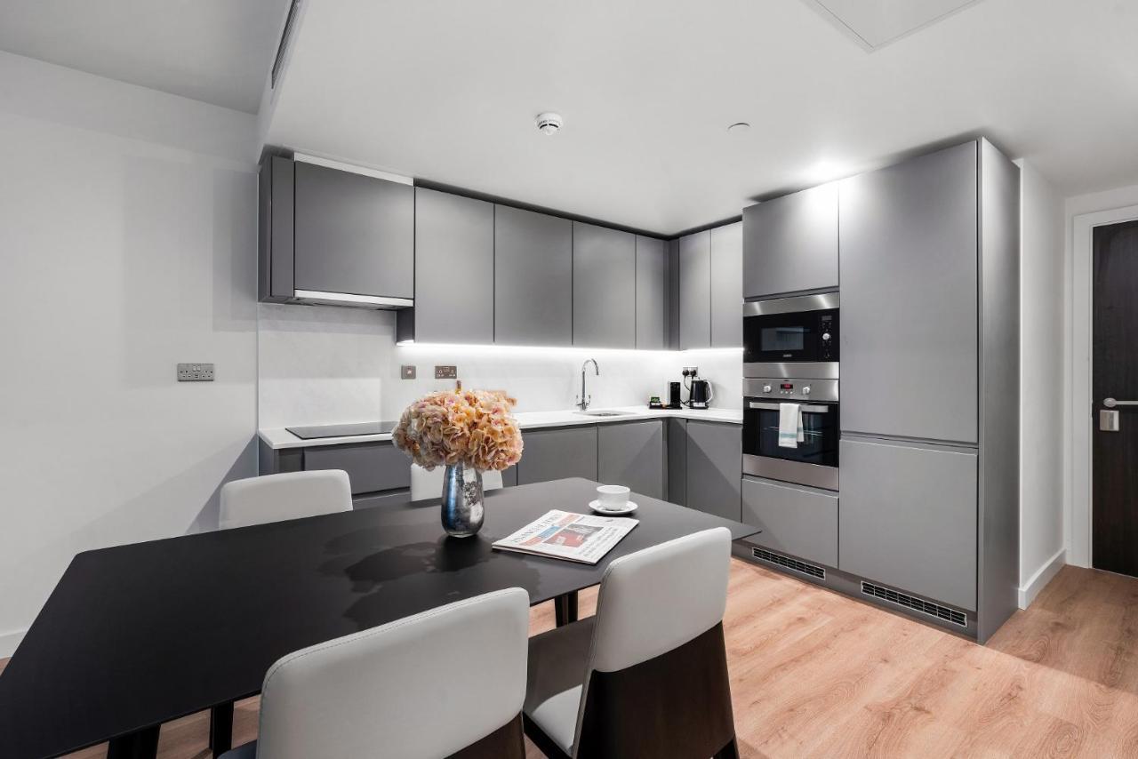 Citysuites 2 Aparthotel Manchester Zewnętrze zdjęcie The photo shows a modern kitchen space. It features sleek, gray cabinetry with a minimalist design. There is a countertop with a sink, and appliances including an oven and a coffee maker. A dining table is positioned near the kitchen area, accompanie
