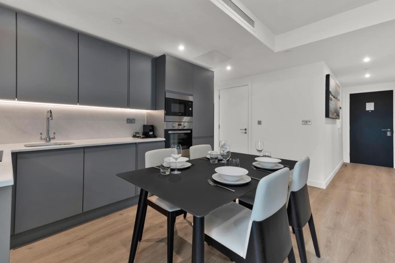 Citysuites 2 Aparthotel Manchester Zewnętrze zdjęcie The photo shows a modern kitchen and dining area. There are sleek gray cabinetry and countertops, with a built-in oven and microwave. The kitchen is well-lit, featuring under-cabinet lighting that adds to the contemporary feel. In the dining area, th